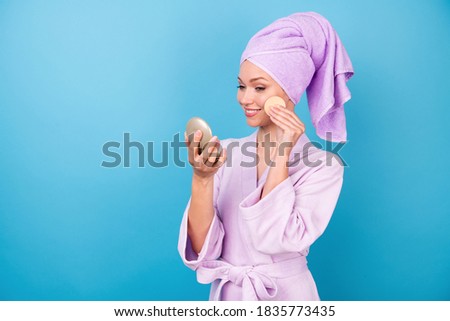 Photo of cute young lady hold look mirror cotton sponge beaming smiling wear violet towel turban bathrobe isolated blue color background.
