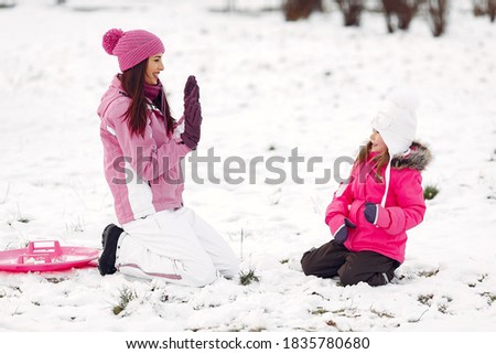 Family in knitted winter hats on family Christmas vacation. Woman and little girl in a park. People playing.