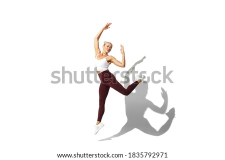 Flying like butterfly. Beautiful young female athlete practicing on white studio background, portrait with shadow. Sportive fit model in motion, action. Body building, healthy lifestyle, style concept