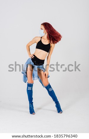 Female dancer in the styles of strip plastic and pole dance with face mask on light background.