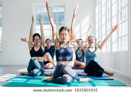 Group of young sporty attractive people practicing yoga lesson with instructor. Instructor woman leading exercise pose, Healthy lifestyle, working out, indoor full length, studio background.