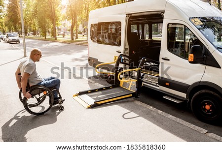 A man in a wheelchair moves to the lift of a specialized vehicle  Royalty-Free Stock Photo #1835818360