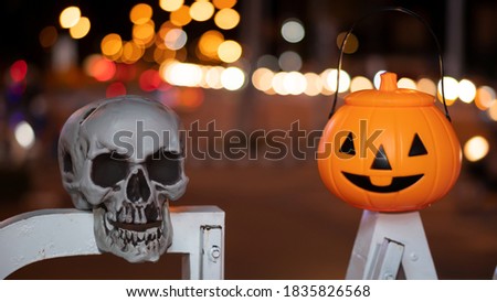 Halloween pumpkin and skull pots are placed on the wood for the scary night, the space has beautiful blurry bokeh.