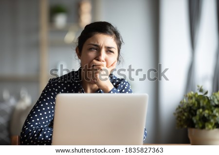 Unmotivated indian employee sitting at desk yawning cover mouth with hand not having interest enthusiasm for work or study. Lack of energy tired student long preparation for exams, overworking concept Royalty-Free Stock Photo #1835827363