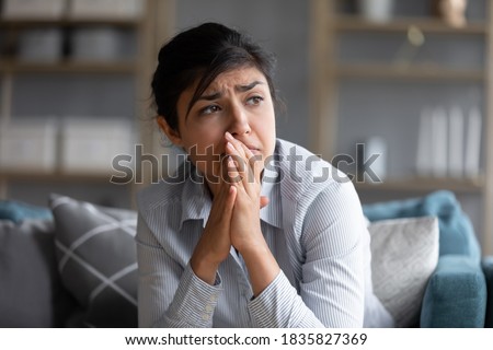 Sad indian woman feels miserable desperate sit on sofa look out the window thinking about personal troubles does not see way out of difficult life situation. Break up, heartbreak, cheated girl concept Royalty-Free Stock Photo #1835827369