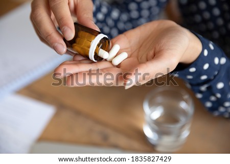 Top above close up view woman pours out from bottle pills into palm. Female takes daily meds complex vitamins for healthy skin nails and hair. Effective treatment, remedy pain killer drugs concept Royalty-Free Stock Photo #1835827429