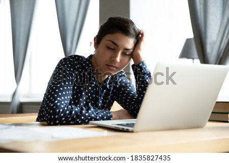 Sleepy indian ethnicity businesswoman fall asleep seated at workplace desk near laptop. Boring job and lack of sleep, unmotivated employee feels disinterested, overworked woman stressful work concept Royalty-Free Stock Photo #1835827435