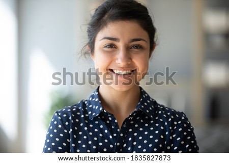 Head shot positive 25s Indian female smiling looking at camera. Successful business woman, career advance of worker, happy student or intern new employee portrait, video call profile picture concept