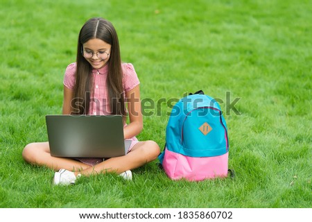 smart smiling teen girl looking at notebook screen with expression of excitement and taking notes, communication in business concept.