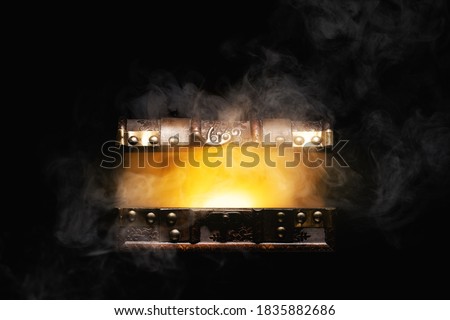 Mysterious treasure chest with light and smoke isolated on black background.