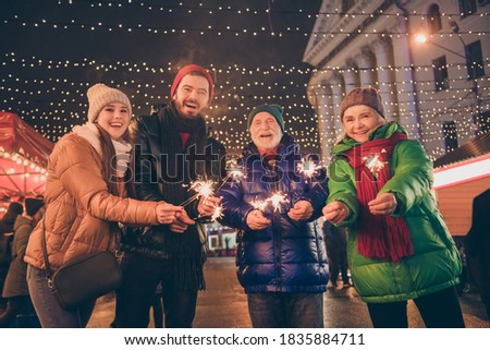 Photo of full family four members x-mas meeting gathering hold fireworks, waiting clock chime last minutes before newyear outerwear hat scarf coat evening street illumination outdoors outside