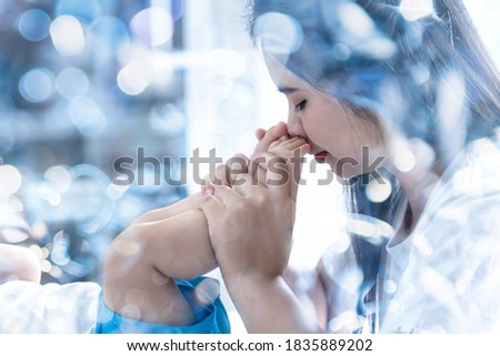Blurred soft images of Asian mother kissed her baby's feet, With love and tie, to Mother's Day and family relationship concept