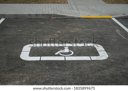 the Parking space for the disabled sign on the asphalt is painted white and the exit point to the sidewalk is painted yellow