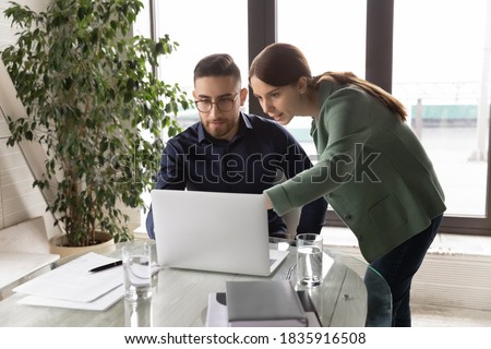 Interested young female employee discussing corporate software with concentrated male arab leader in eyeglasses. Professional diverse multiracial managers involved in project development on computer. Royalty-Free Stock Photo #1835916508