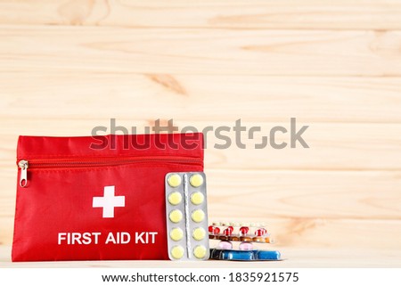First aid kit with colorful pills on brown wooden table