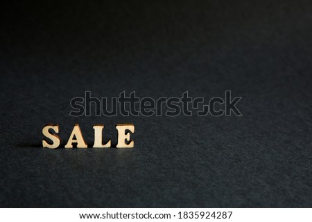 inscription "Sale" of wooden letters on a black background. Black Friday, discounts, sale, shopping, interest sign. Space for text