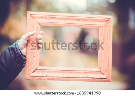 Wooden square vintage retro picture frame in artist's hand