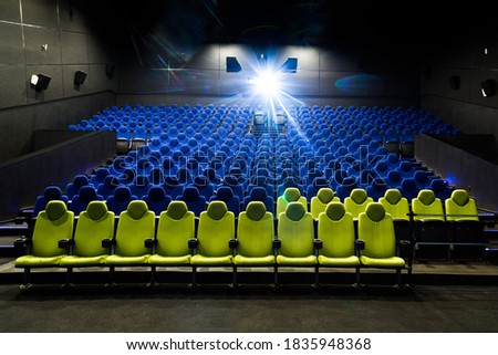 Cinema theatre interior with blue and yellow seats while projecting a movie. Wide shot view on an empty auditorium while screening a film stock photo
