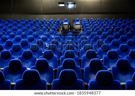 Cinema theatre interior with blue and yellow seats while projecting a movie. Wide shot view on an empty auditorium while screening a film stock photo