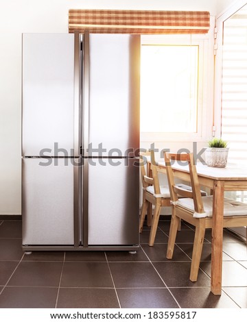 Luxury steel refrigerator on the kitchen, bright sun light from the windows, beautiful apartment interior, stylish fridge, wealth concept