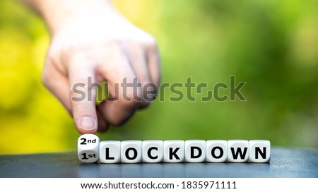 Symbol for a second lockdown. Hand turns dice and changes the expression "1st lockdown" to "2nd lockdown". Royalty-Free Stock Photo #1835971111