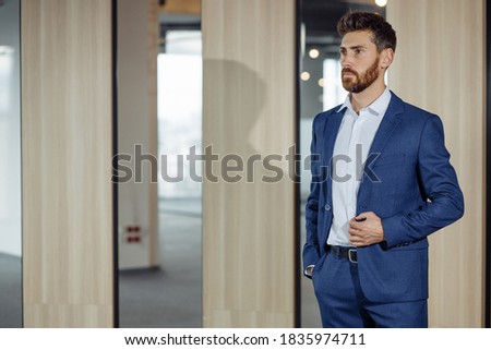 Handsome man with a red beard, wearing a blue suit, a stylish and refined man.