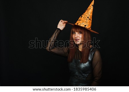 Portrait of winsome, blonde lady look at camera on black background. Photo of cute woman wearing conical hat