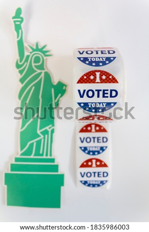 Roll of I Voted Today stickers and statue of liberty on white background. US presidential election concept
