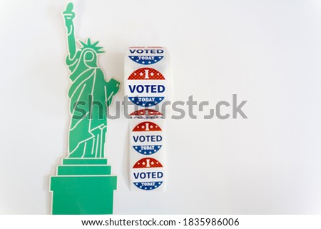 Roll of I Voted Today stickers and statue of liberty on white background with copy space. US presidential election concept