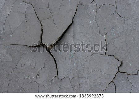 Peeling paint on the wall. Old concrete wall with cracked flaking paint. Weathered rough painted surface with patterns of cracks and peeling. High resolution texture for background and design. Closeup Royalty-Free Stock Photo #1835992375