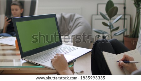 View over head on of caucasian woman holding pc notebook computer with green screen while watching something and working from home. Chroma key