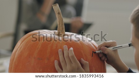 Close-up of kid drawing halloween holiday decoration on punpkin . Social campaign for pandemic coronavirus covid-19 prevention.