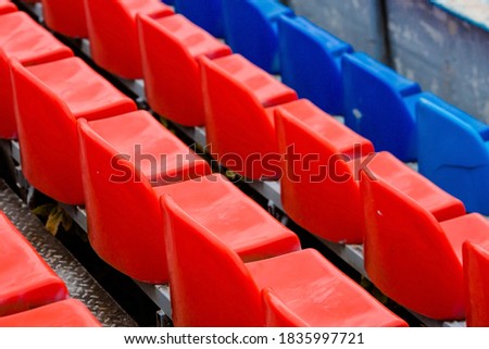 Empty seats in the stands of the arena or auditorium. Rows of red and white stadium seats without spectators. The concept of the abolition of sports and mass entertainment events.