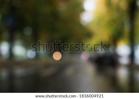Blurry image through the car window. Autumn landscape of the city during the rain