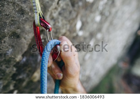 Close up of rock climber hand clipping rope in a quick draw caribener on a cliff face Royalty-Free Stock Photo #1836006493