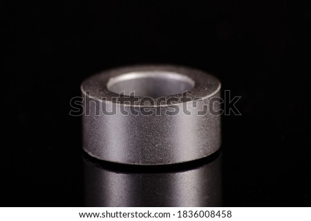 Ferrite core ring in the shape of toroid isolated on the black reflective background Royalty-Free Stock Photo #1836008458