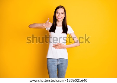Portrait of positive cheerful girl touch hand abdomen enjoy healthy, digestive nutrition show thumb up sign wear white denim isolated over shine color background Royalty-Free Stock Photo #1836021640
