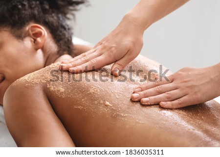 African american relaxed lady having skin scrubbing procedure at spa salon, closeup. Spa therapist applying exfoliating body mask on sleeping black woman back at luxury spa, body care concept Royalty-Free Stock Photo #1836035311