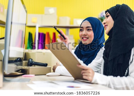 Portrait of smiling beautiful two muslim owner asian woman freelancer sme business online shopping working on laptop computer with parcel box on table at home - Business online shipping and delivery