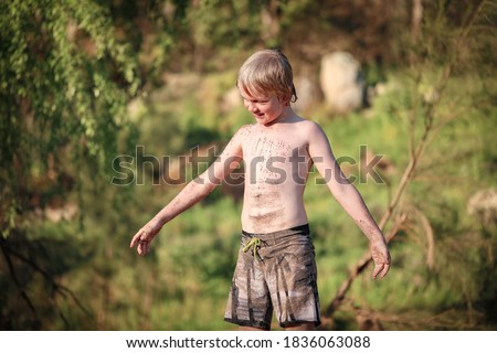 Young boy covered in sand playing on riverbed
