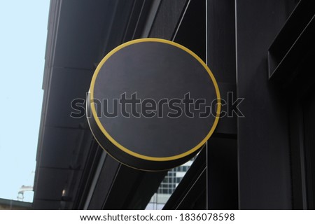 Modern blank generic outdoor round sign outside a restaurant or retail store. Dark grey in colour