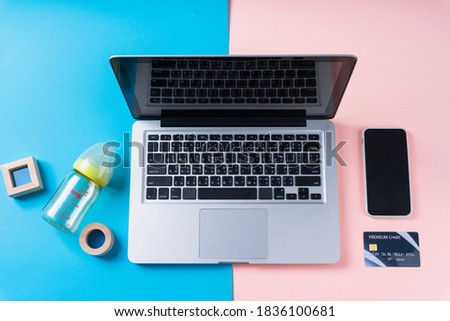 Computer laptop with empty screen on blue and pink background with milk bottle and credit card and smartphone.