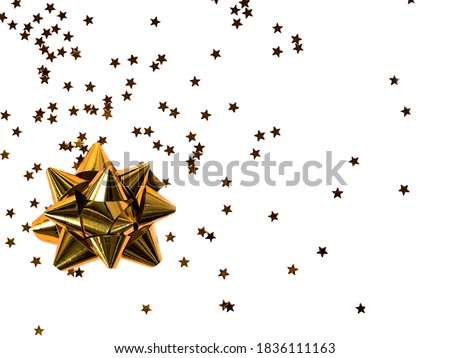 Gold bow with star glitter confetti on white background. Festive twinkle glitter background.