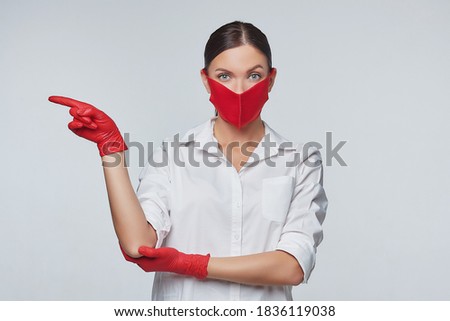 young girl wearing gloves and a face mask. makes a sign with her index finger. The concept of prevention of covid 19 coronavirus. Photo session in the Studio on a white background