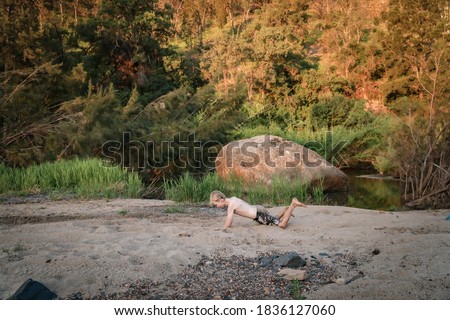 Young boy covered in sand playing on riverbed