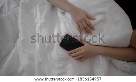 Mobile phone and social media addiction, Woman hand holding smart phone during sleeping.