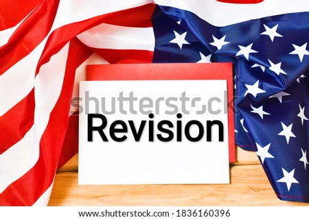 REVISION written text in a notebook against the background of the American flag on a wooden background. Business concept. 