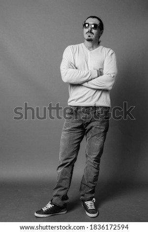Handsome man with curly hair and mustache against gray background