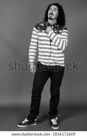 Handsome man with curly hair and mustache against gray background