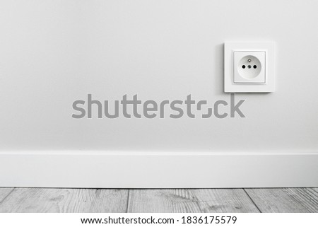 Electrical socket isolated on gray wall. Renovated studio apartment power supply background. Empty copy space single white plastic power outlet. Royalty-Free Stock Photo #1836175579
